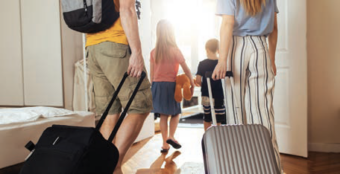 A family walking through a room with luggage.